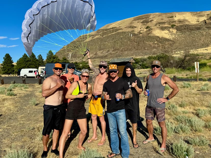 Wing foilers on dry lakebed with golden hills